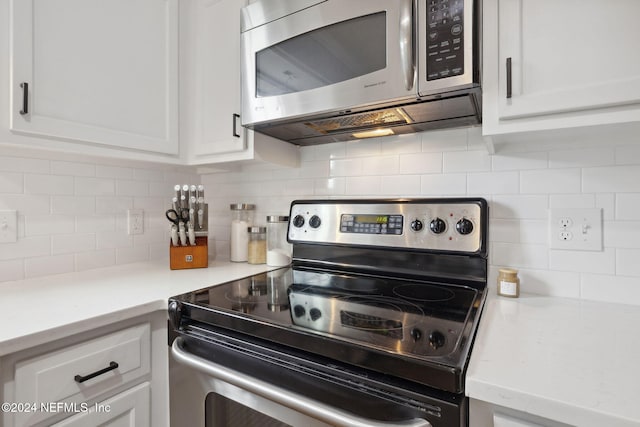 kitchen featuring decorative backsplash, white cabinetry, and stainless steel appliances