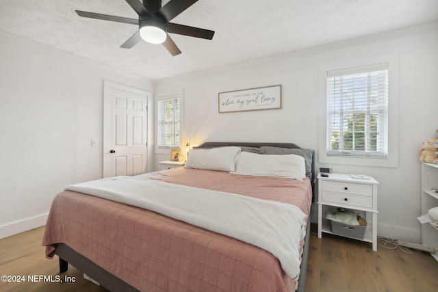 bedroom with dark hardwood / wood-style floors, multiple windows, ornamental molding, and ceiling fan