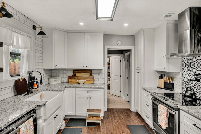 kitchen featuring white cabinets, stainless steel appliances, wall chimney range hood, and dark hardwood / wood-style flooring