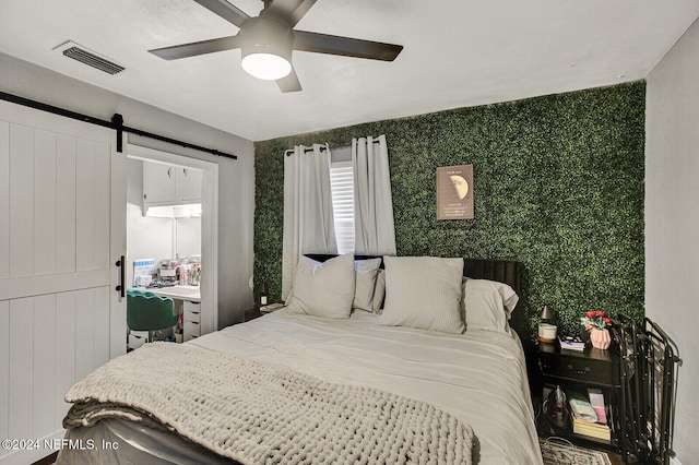 bedroom with a barn door and ceiling fan