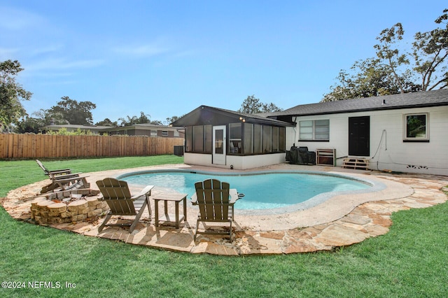 view of pool with a patio, a lawn, a sunroom, and an outdoor fire pit