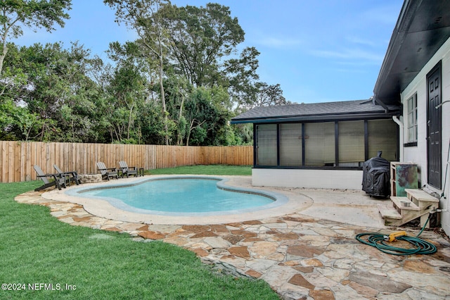 view of swimming pool with a lawn, a sunroom, and a patio area