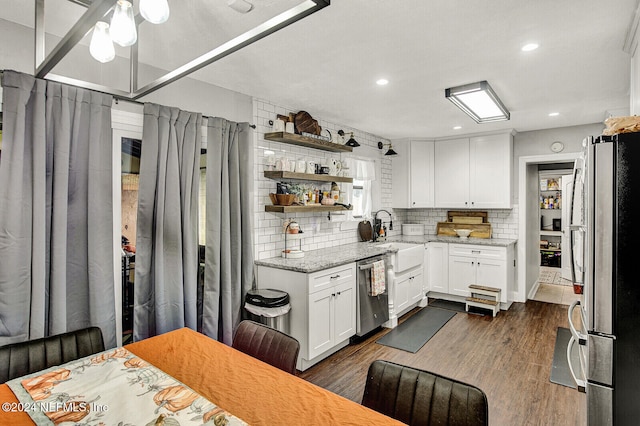 kitchen with appliances with stainless steel finishes, dark hardwood / wood-style flooring, decorative backsplash, sink, and white cabinets