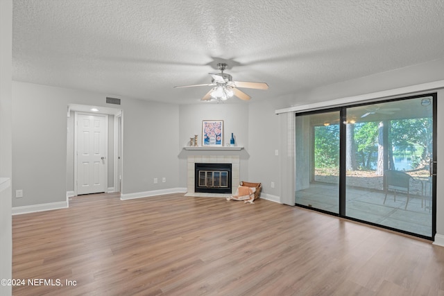 unfurnished living room with a tile fireplace, a textured ceiling, and light wood-type flooring