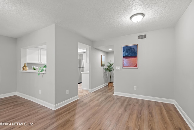 spare room with light hardwood / wood-style floors and a textured ceiling