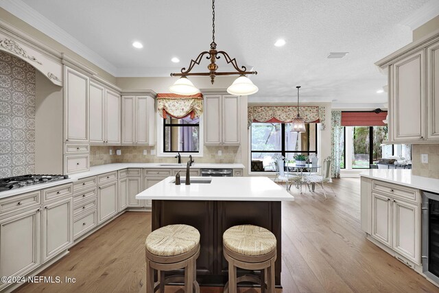 kitchen featuring a kitchen bar, a kitchen island with sink, light hardwood / wood-style flooring, and pendant lighting