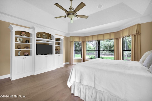 bedroom featuring a raised ceiling, multiple windows, ceiling fan, and dark hardwood / wood-style flooring