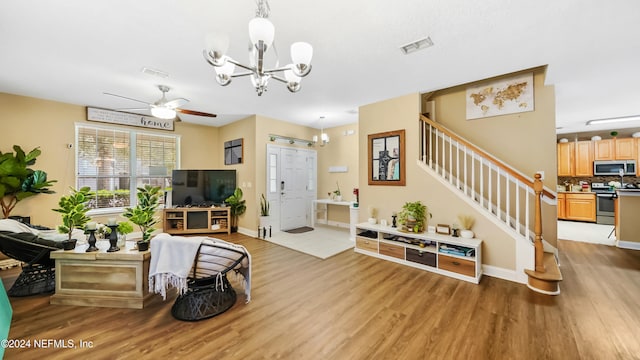 living room featuring light wood-type flooring and ceiling fan with notable chandelier