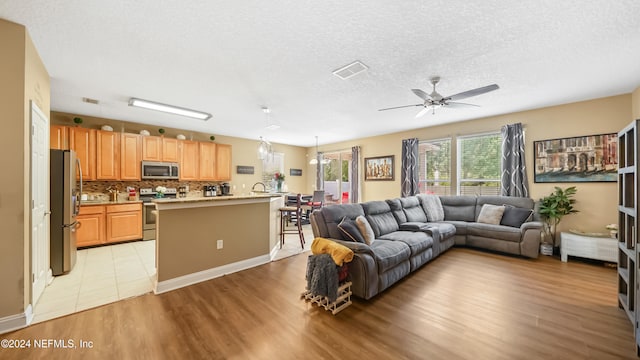 living room featuring a textured ceiling, light hardwood / wood-style floors, and ceiling fan