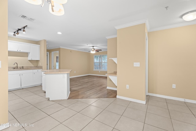 kitchen featuring light hardwood / wood-style floors, white cabinetry, a kitchen island, and ornamental molding