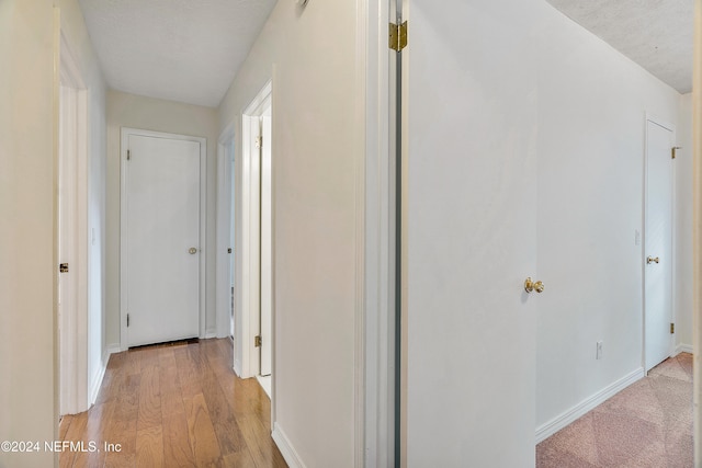 hall with light hardwood / wood-style flooring and a textured ceiling