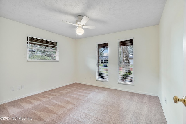 carpeted empty room featuring a textured ceiling, a healthy amount of sunlight, and ceiling fan