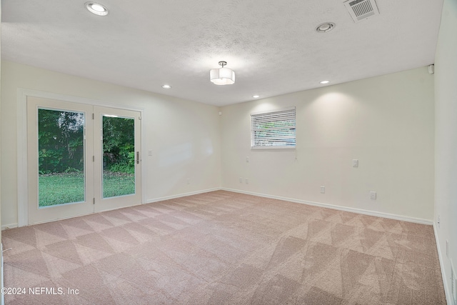 spare room with light colored carpet and a textured ceiling