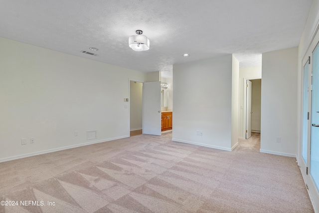 unfurnished room featuring light colored carpet and a textured ceiling