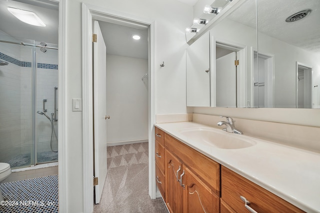 bathroom featuring toilet, vanity, and a shower with door