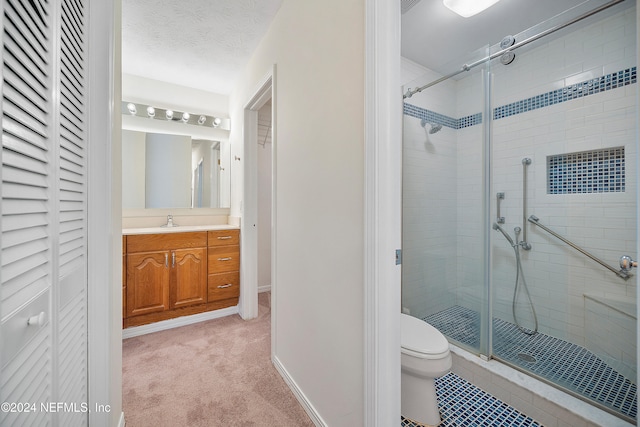 bathroom with toilet, vanity, a textured ceiling, and a shower with door