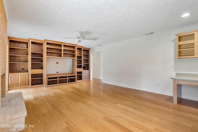 unfurnished living room with a textured ceiling, wood-type flooring, ceiling fan, and a fireplace