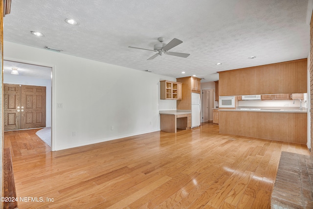 unfurnished living room with light hardwood / wood-style floors, ceiling fan, and a textured ceiling