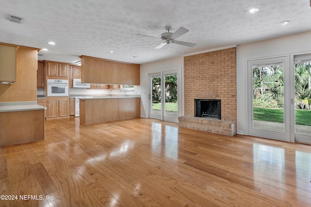 kitchen featuring light wood-type flooring, a wealth of natural light, a textured ceiling, and white appliances