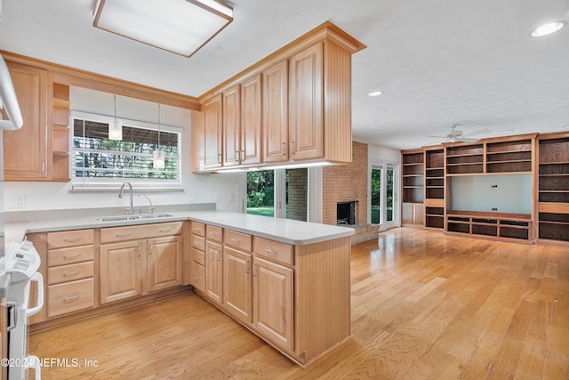 kitchen with light hardwood / wood-style floors, sink, kitchen peninsula, light brown cabinets, and pendant lighting