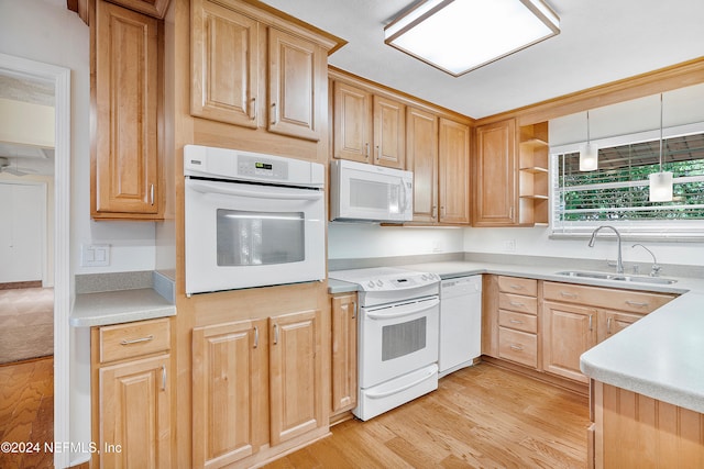 kitchen with sink, light brown cabinets, light wood-type flooring, white appliances, and decorative light fixtures