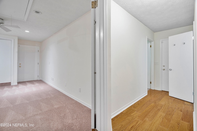 hall with a textured ceiling and light hardwood / wood-style floors