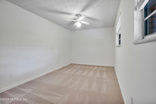 carpeted spare room featuring a textured ceiling and ceiling fan