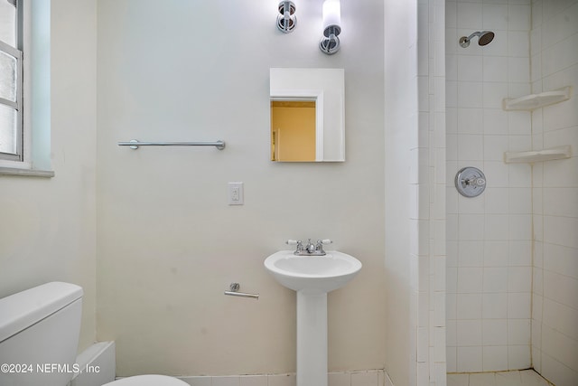 bathroom with toilet, sink, and a tile shower