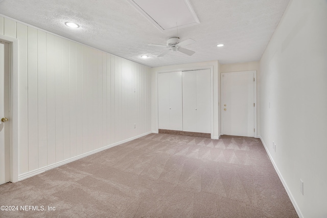 unfurnished bedroom with a textured ceiling, light colored carpet, ceiling fan, and a closet