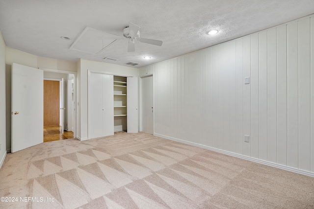 unfurnished bedroom with a closet, a textured ceiling, light colored carpet, and ceiling fan