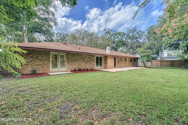 rear view of house featuring a lawn and a patio