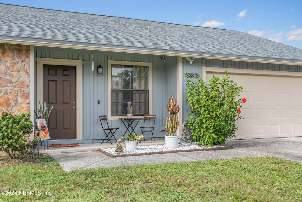 entrance to property featuring a garage and a yard