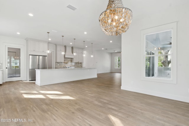 unfurnished living room with light wood-type flooring, visible vents, an inviting chandelier, and recessed lighting