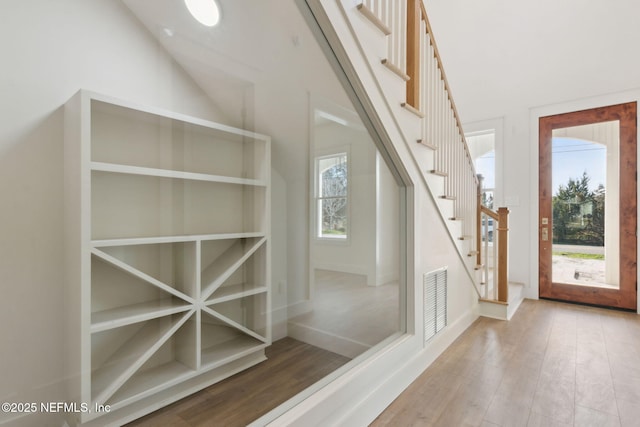 interior space featuring wood finished floors, visible vents, a towering ceiling, and baseboards