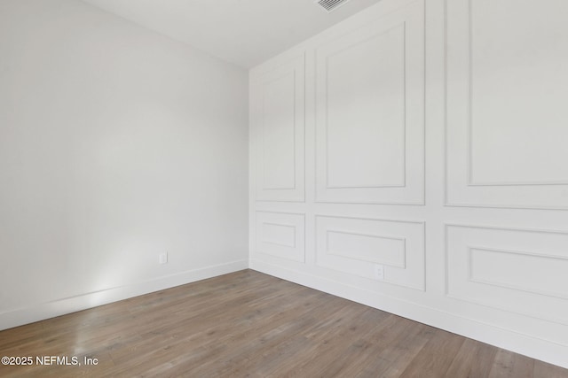 spare room featuring visible vents, baseboards, and wood finished floors