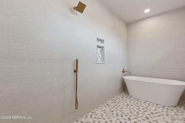 bathroom with a soaking tub and tiled shower