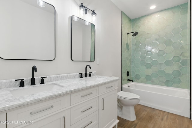 bathroom with toilet, wood finished floors, bathtub / shower combination, and a sink