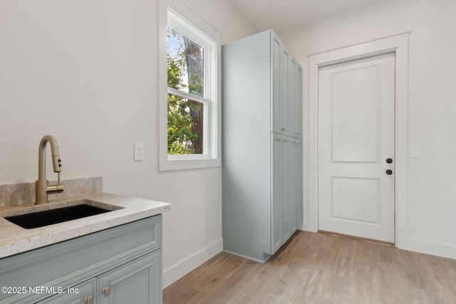 washroom with light wood-style flooring, baseboards, and a sink