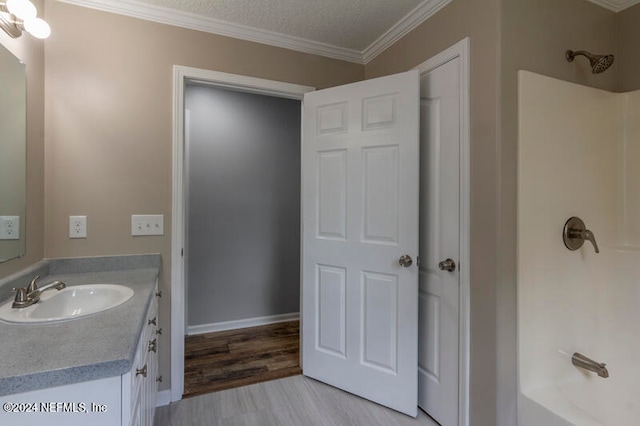 bathroom featuring crown molding, vanity, a textured ceiling, shower / bathing tub combination, and hardwood / wood-style flooring