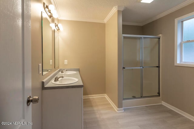 bathroom featuring a textured ceiling, wood-type flooring, vanity, an enclosed shower, and crown molding