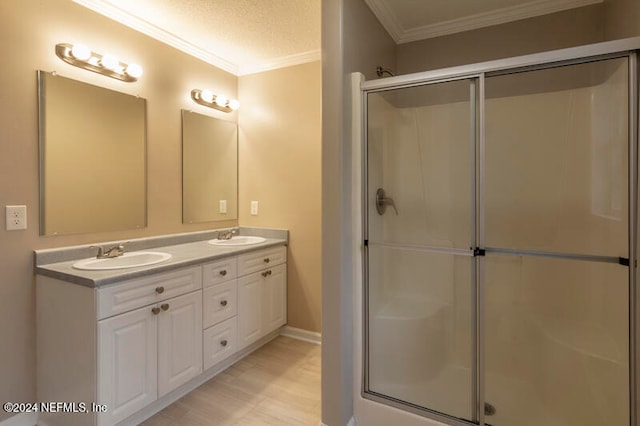 bathroom with vanity, an enclosed shower, a textured ceiling, and crown molding