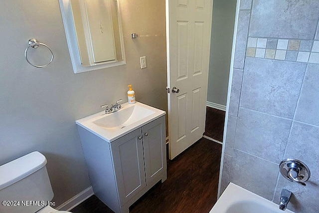 full bathroom featuring vanity, wood-type flooring, washtub / shower combination, and toilet