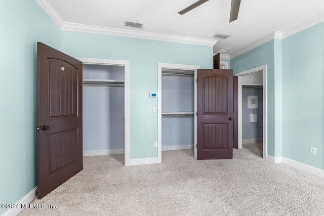 unfurnished bedroom featuring light carpet, ceiling fan, crown molding, and two closets