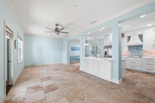 kitchen with sink, stainless steel refrigerator with ice dispenser, custom exhaust hood, white cabinets, and decorative backsplash