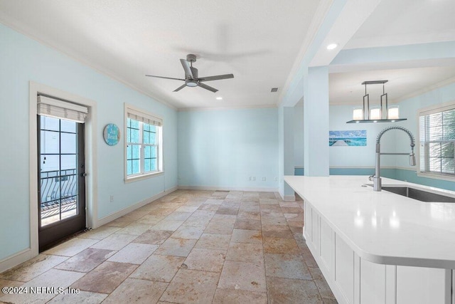 kitchen featuring ornamental molding, hanging light fixtures, sink, white cabinets, and a kitchen island with sink