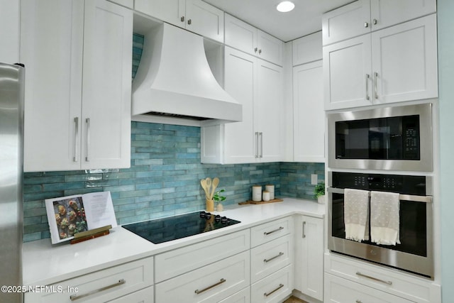 kitchen featuring appliances with stainless steel finishes, white cabinetry, light countertops, and custom range hood