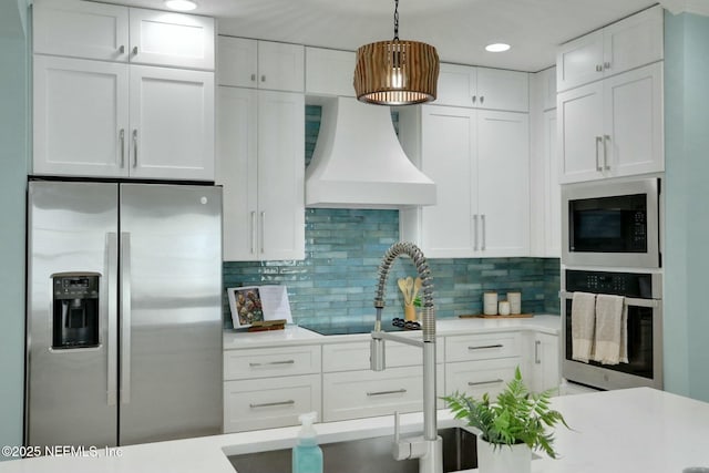 kitchen with white cabinets, appliances with stainless steel finishes, light countertops, and custom range hood