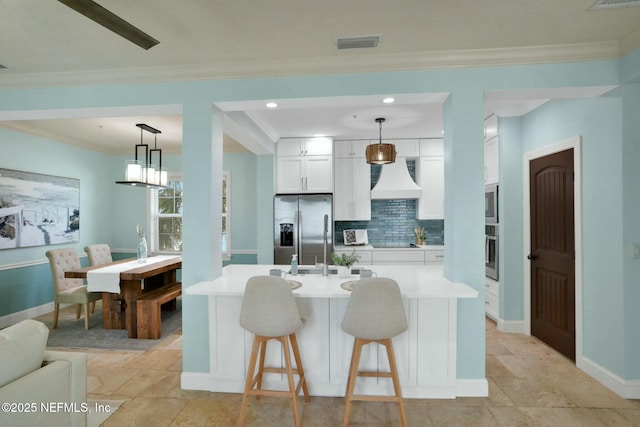 kitchen featuring visible vents, custom range hood, backsplash, stainless steel appliances, and white cabinets