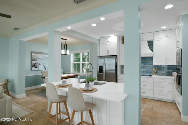 kitchen with visible vents, a sink, stone tile flooring, appliances with stainless steel finishes, and crown molding