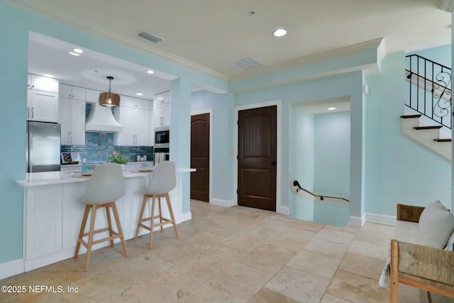 kitchen featuring visible vents, backsplash, light countertops, appliances with stainless steel finishes, and custom exhaust hood